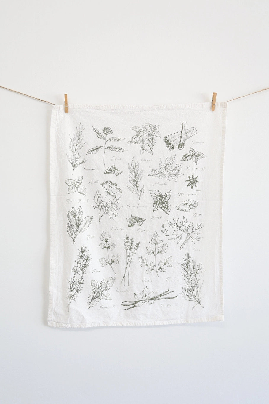 White tea towel with images of herbs and spices.