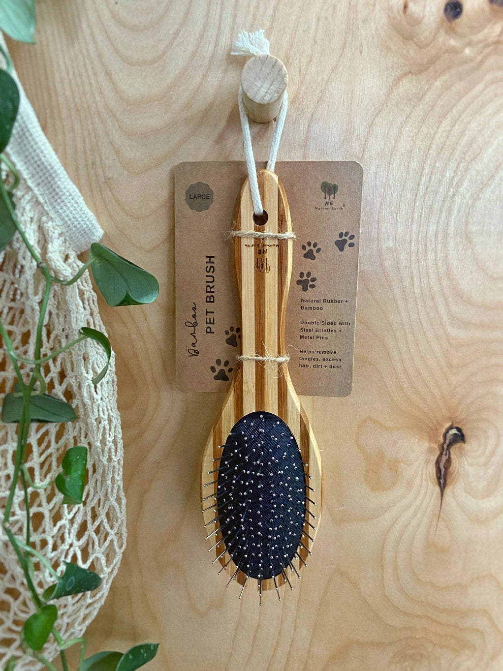 A large wooden pet brush dangling on a wooden hook.