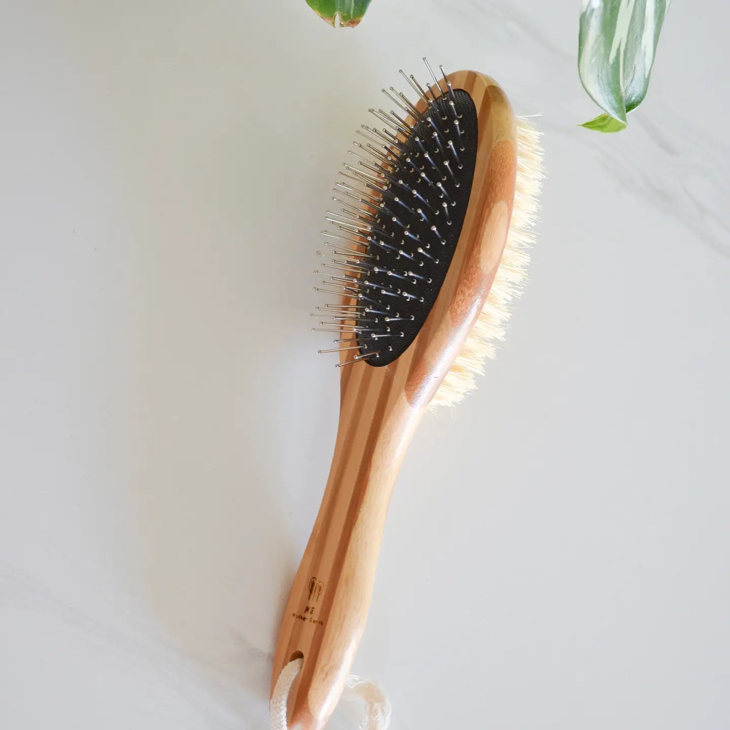 Bamboo pet brush laying on its side showing metal pin and bristle sides.