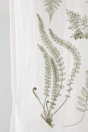 Close up of a white tea towel with fern fronds.