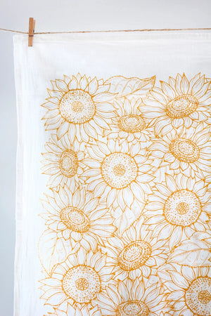 close up of a white tea towel with yellow sun flowers.