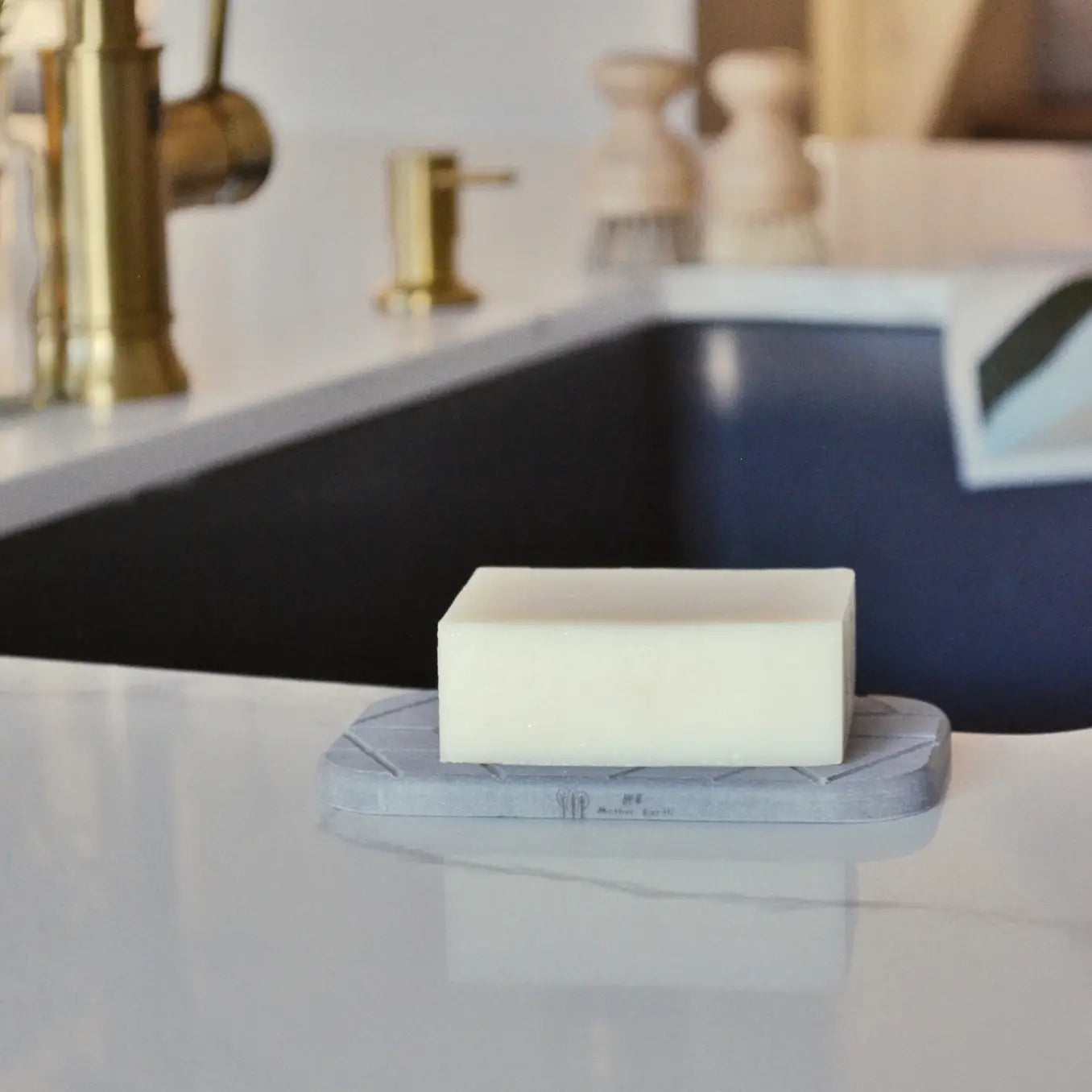 Soap sitting on a diatomite soap tray. Tray on the counter near a sink.