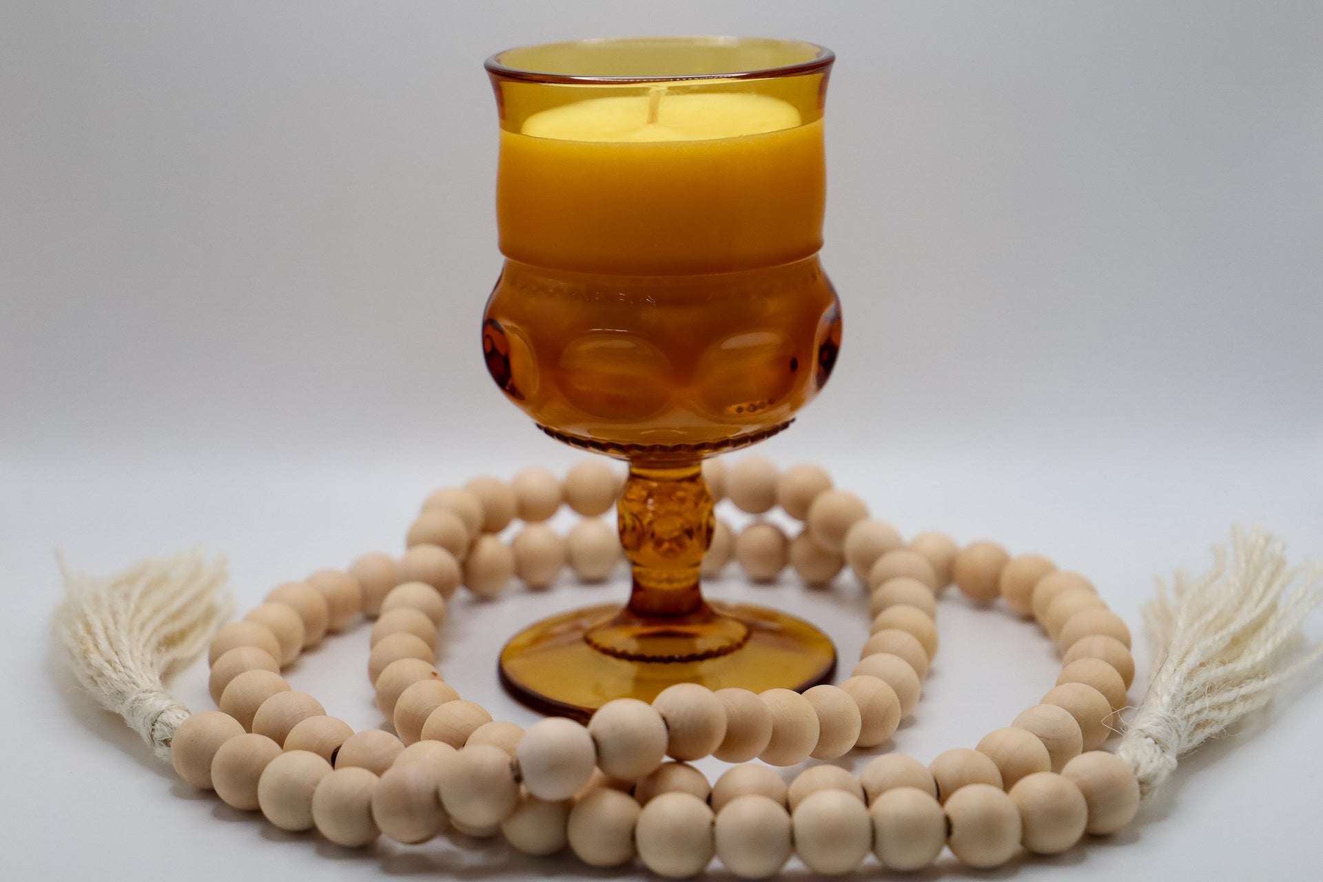 Mid Century Amber Color Crown by Colony water goblet with soy candle scented in Black Amber and Plum