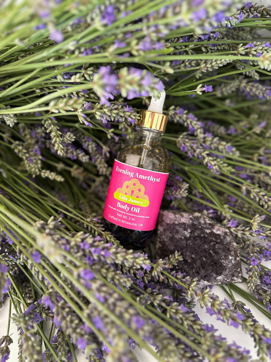 Lavender flowers with a bottle of Lola James body oil and amethyst crystals laying on top.