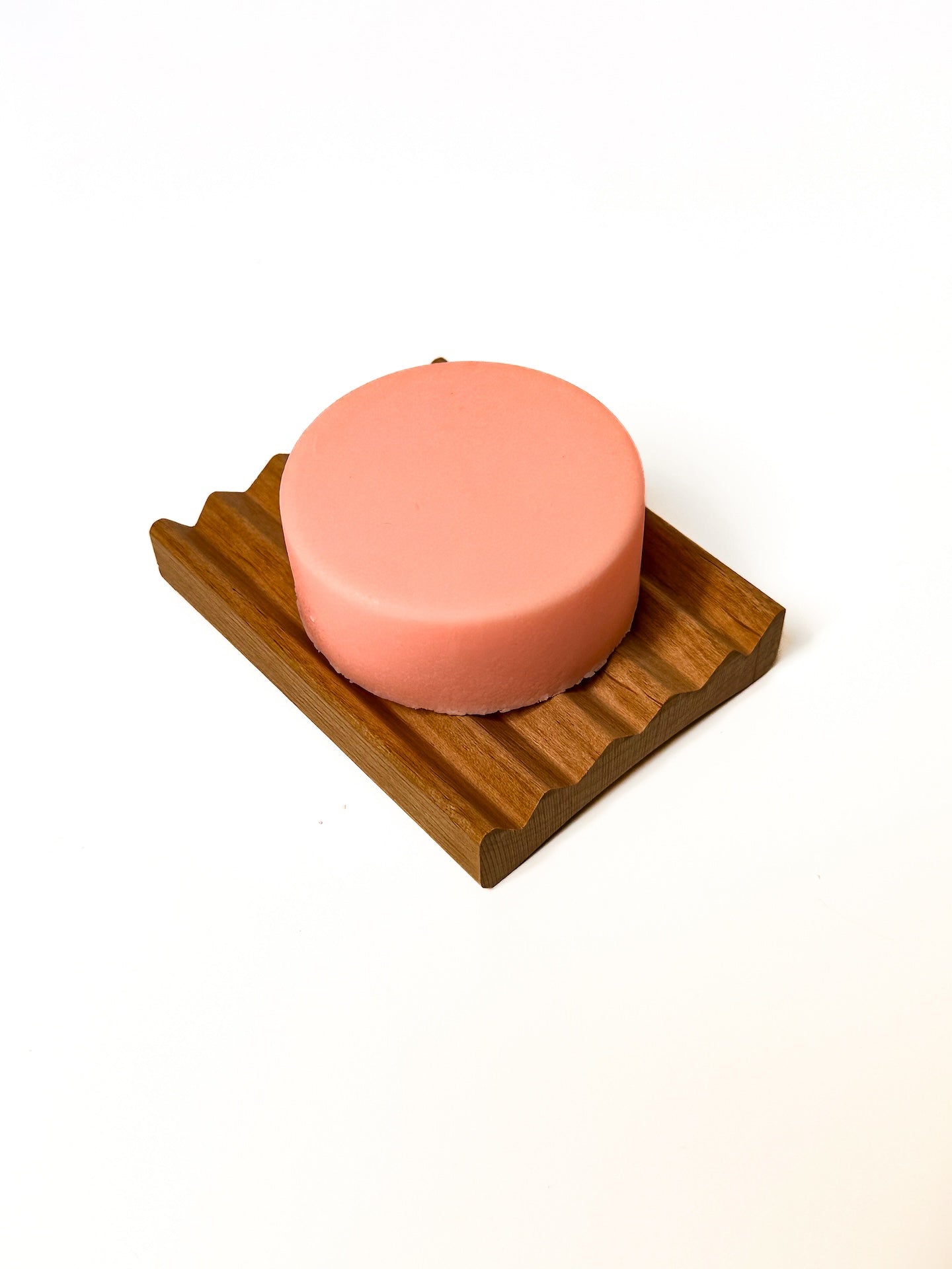 Pink body butter bar on a wooden tray.