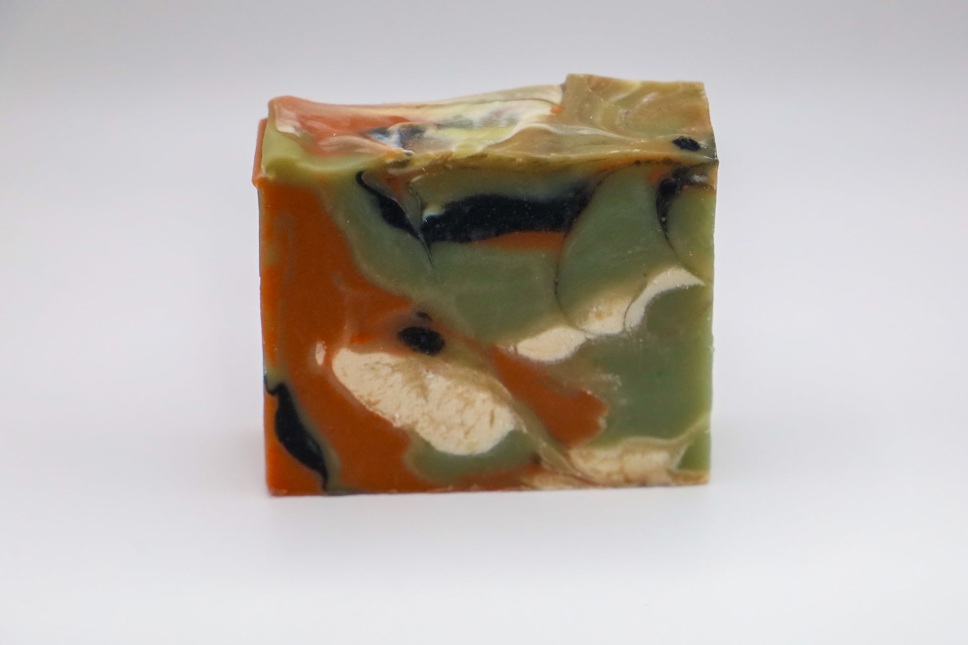 Handmade soap with green, orange, black and white swirls resembling onyx, scented with matcha and apricot
