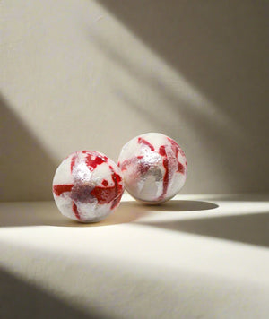 2 white bath bombs with red and silver paint.