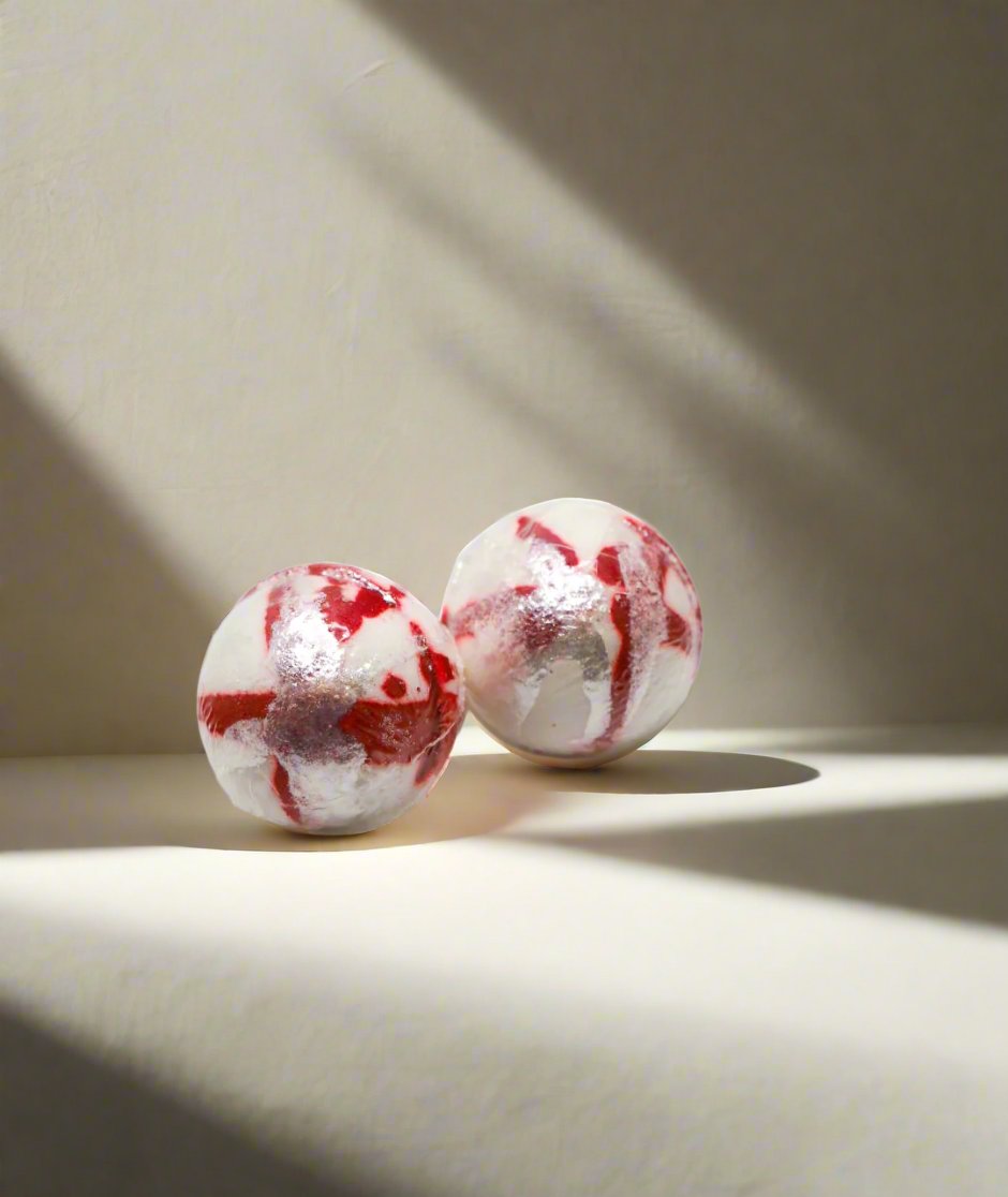 2 white bath bombs with red and silver paint.