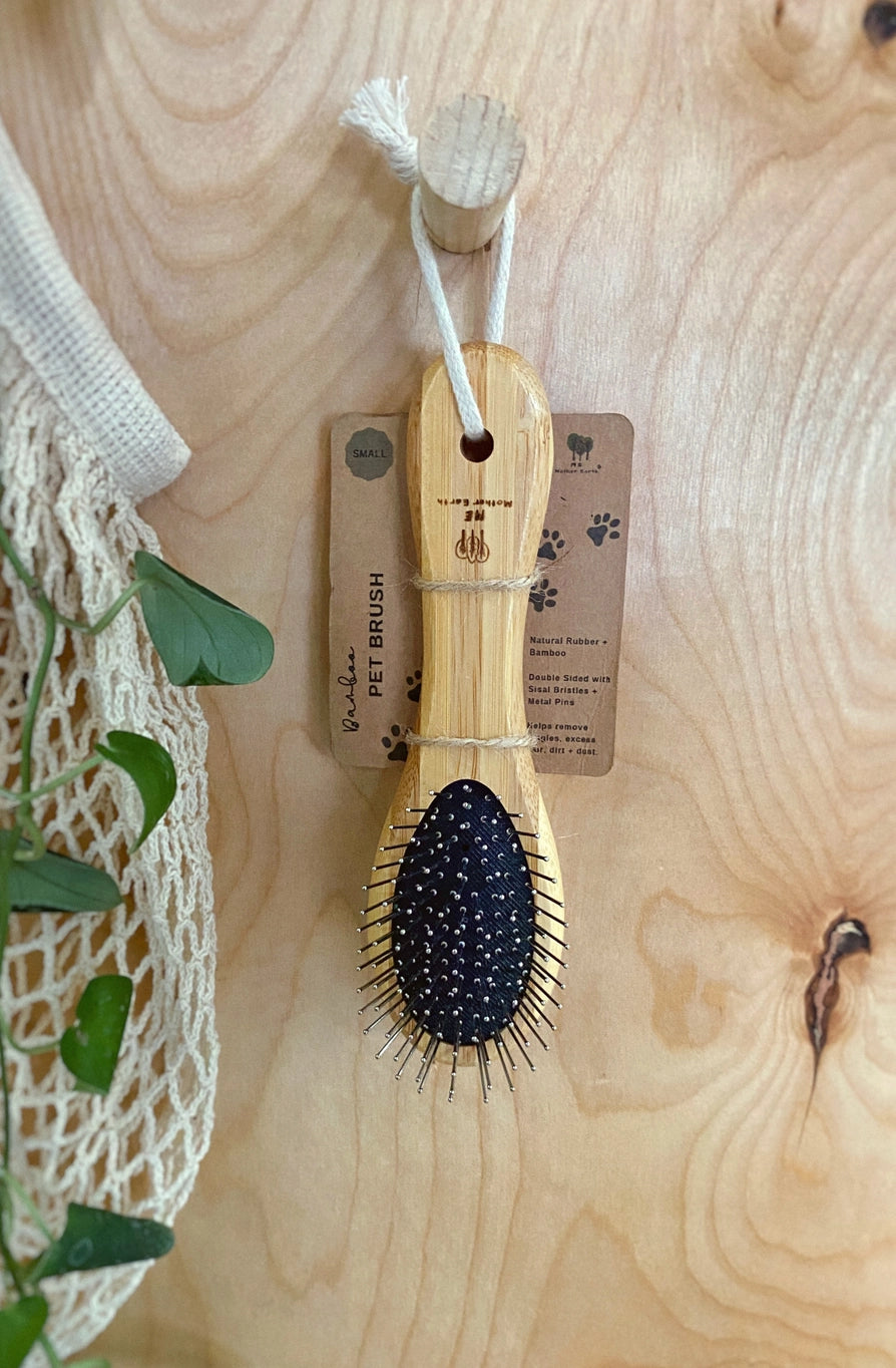 A small Bamboo pet brush hanging on a wooden hook.