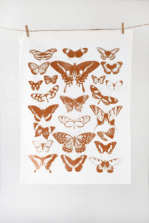 White tea towel with rows of terra cotta colored butterflies